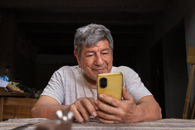 Elderly Colombian man chatting with family via smartphone at home
